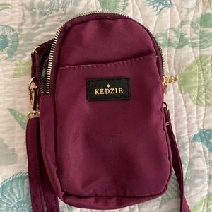 Purple crossbody bag with front pocket and two zipper pockets. 8 inches.